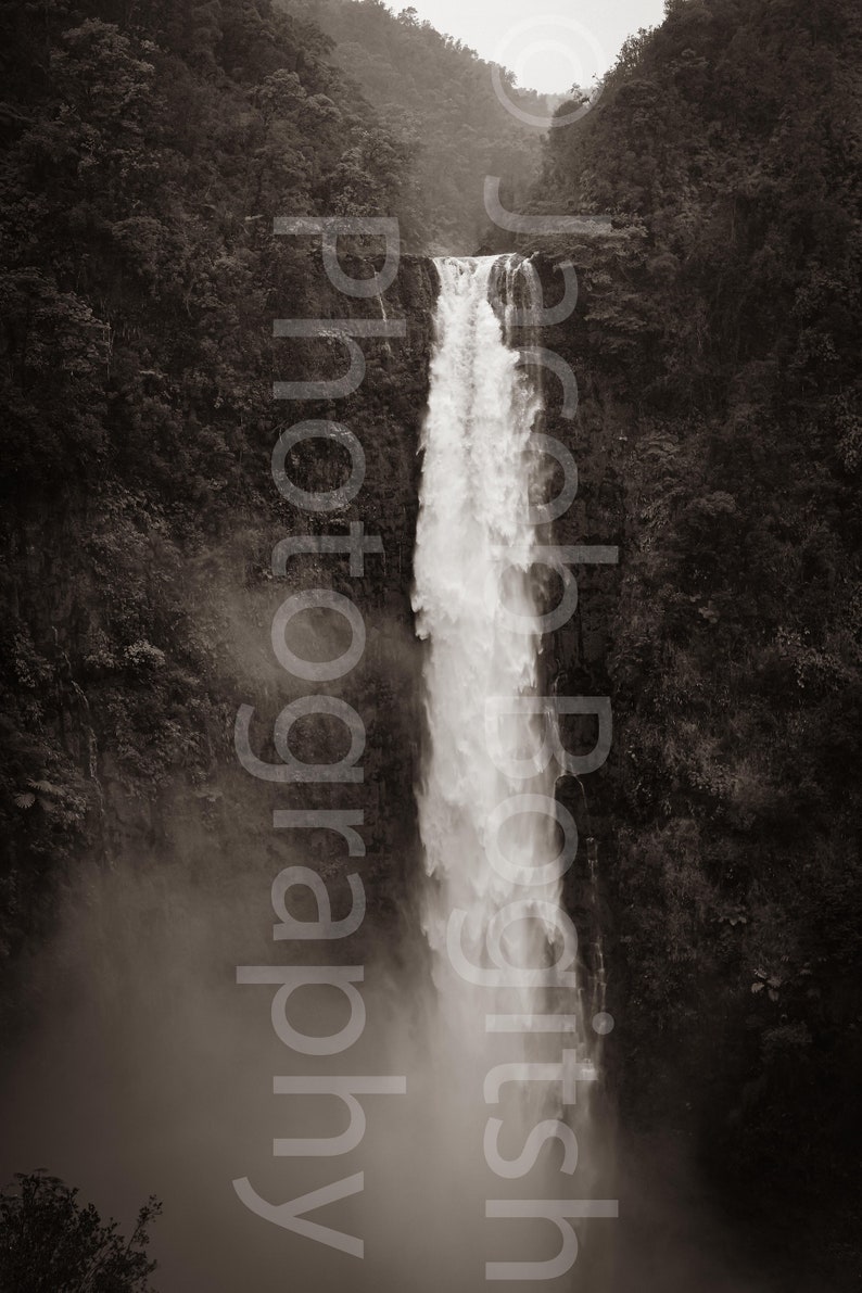 May include: A black and white photograph of a waterfall cascading down a steep cliff face. The waterfall is surrounded by lush greenery.