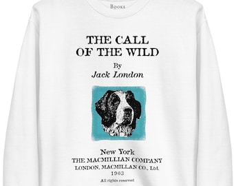 Op de afbeelding: Witte trui met een zwart-witte illustratie van een hondenkop op een blauwe achtergrond. De tekst "The Call of the Wild" van Jack London is op de trui gedrukt.