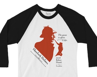 Pode incluir: Camiseta de beisebol branca e preta com uma silhueta vermelha de Sherlock Holmes fumando um cachimbo. A camisa inclui o texto "Sherlock Holmes", "The game is afoot" e "221B Baker Street, London".