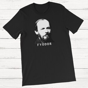 K&ouml;nnte beinhalten: Schwarzes T-Shirt mit einem wei&szlig;en und grauen Bild von Fjodor Dostojewski, einem ber&uuml;hmten russischen Autor, und dem Wort "FYODOR" unter dem Bild.