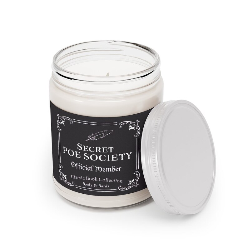 May include: A white candle in a glass jar with a black label that reads "Secret Poe Society Official Member Classic Book Collection Books & Barrels". The jar has a silver lid.