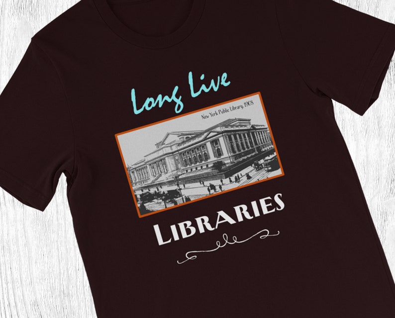 K&ouml;nnte beinhalten: Ein dunkelmarrones T-Shirt mit einem Vintage-Schwarzwei&szlig;bild des Geb&auml;udes der New Yorker &ouml;ffentlichen Bibliothek. Der Text "Long Live Libraries" ist in Wei&szlig; unter dem Bild mit einem dekorativen Schn&ouml;rkel gedruckt.