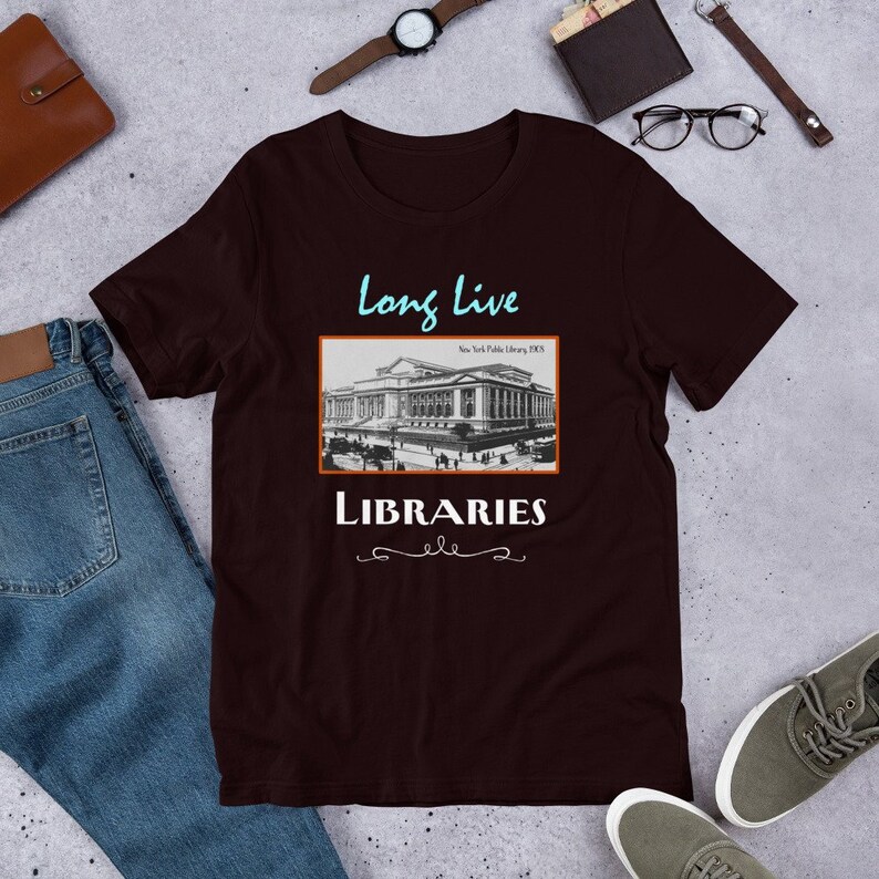 K&ouml;nnte beinhalten: Ein dunkelbraunes T-Shirt mit einem Vintage-Postkartenbild der New Yorker &ouml;ffentlichen Bibliothek. Der Text "Long Live Libraries" ist unter dem Bild gedruckt.