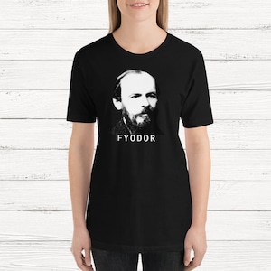 K&ouml;nnte beinhalten: Schwarzes T-Shirt mit einem wei&szlig;en Bild von Fjodor Dostojewski und dem Text "FYODOR" darunter.