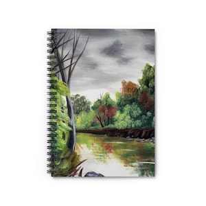 May include: Spiral-bound notebook featuring a landscape painting of a river scene. The artwork depicts a river reflecting the surrounding trees in shades of green, red, and yellow, under a cloudy gray sky. The notebook's binding is black.