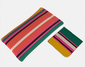 May include: A striped glasses case with a matching cleaning cloth. The case is made of a soft, colorful fabric with pink, white, black, and green stripes. The cleaning cloth is a smaller version of the case with the same pattern.