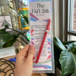 May include: A red and silver Fid'l Stik tool in a clear plastic package. The package has text that reads "The Fid'l Stik By Creator's". The tool is designed for making jump rings and is made in the USA.