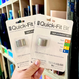 May include: Two Quick-Fit replacement bits for glass work are shown. Each package contains a silver cylindrical bit and product information. The packaging includes a colour-coded grit guide and diameter measurements in mm.