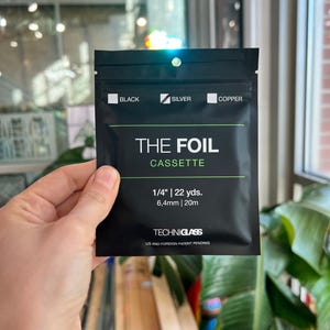 Può includere: Cassetta di lamina nera con la scritta "THE FOIL CASSETTE". La confezione include lamina da 1/4", 22 yds (20m) di lunghezza e 6,4 mm. La confezione riporta anche le parole "BLACK", "SILVER" e "COPPER".