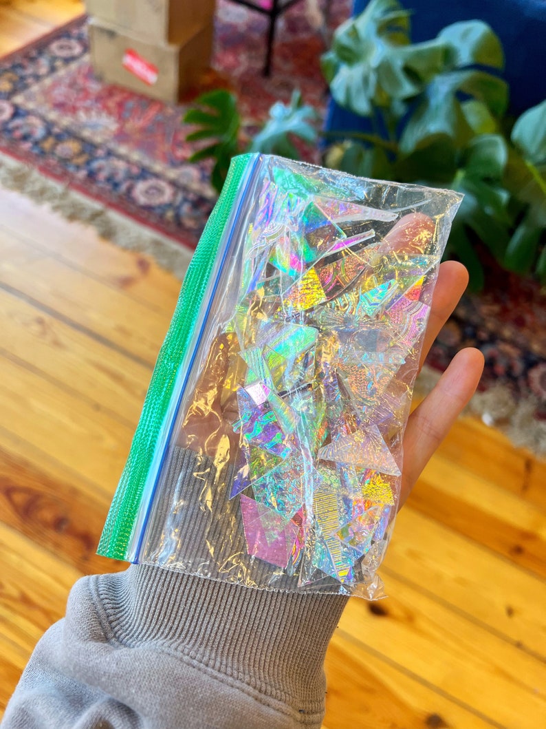 May include: A clear plastic bag filled with iridescent holographic triangle shapes.