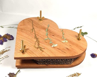 May include: A heart-shaped wooden frame with a cardboard insert, designed for pressing flowers. The frame has four brass screws and is decorated with pressed flowers.