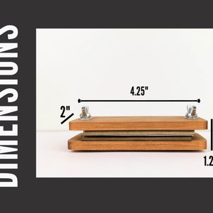 May include: A wooden flower press with metal hardware. The press is rectangular, with dimensions of 4.25 inches wide, 2 inches high, and 1.25 inches deep. The press is designed for pressing flowers and other botanical specimens.