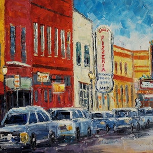 May include: A painting depicting a city street scene with a red brick building, a white building with a sign that reads "Bacci Pizzeria", and a yellow building with a sign that says "Playhouse". Cars are parked on the street.