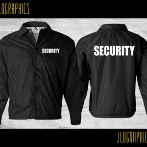 Op de afbeelding: Zwarte nylon jas met een witte "SECURITY" tekst op de voor- en achterkant. De jas heeft een knoopsluiting en een kraag.