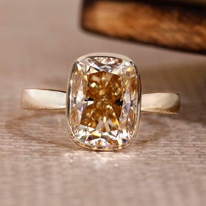 3,63 ct champagnefärgad förlängd moissanit i kuddslipad form, förlovningsring i gult guld, brudring med rakt skaft och solitaire