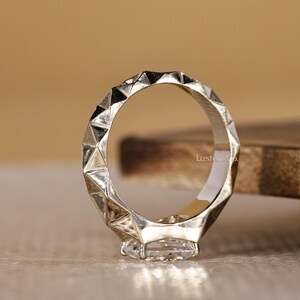 May include: A white ceramic mug with a black handle and the text "But First, Coffee" in a bold, black font. The mug is set against a blurred background, suggesting a cozy setting.