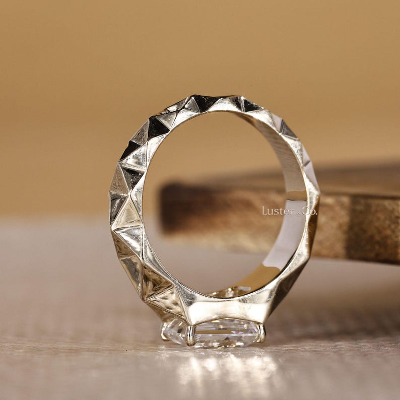 May include: A white ceramic mug with a black handle and the text "But First, Coffee" in a bold, black font. The mug is set against a blurred background, suggesting a cozy setting.