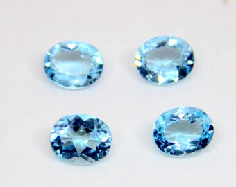 May include: Four oval-shaped, light blue gemstones on a white background.