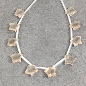 May include: A strand of light brown star-shaped gemstone beads with a black tassel at the top.