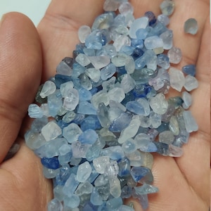 May include: A small pile of light blue, blue, and clear gemstone chips. The chips are various sizes and shapes.