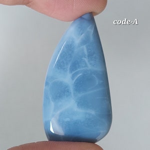 May include: A light blue cabochon gemstone with a white marbled pattern. The gemstone is teardrop shaped and has a smooth, polished surface. code-A