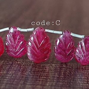 May include: A strand of pink gemstone beads, each carved in the shape of a leaf. The beads are strung on silver wire. The text "code: C" is visible in the image.