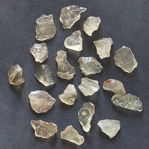 Puede incluir: Una colección de 20 chips de piedras preciosas naturales translúcidas, de color amarillo claro, de forma irregular. Los chips son de varios tamaños y formas, algunos tienen un ligero tono naranja.