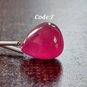 Pode incluir: Um pingente de pedra preciosa rosa brilhante em forma de lágrima com uma corrente de prata. Código: F