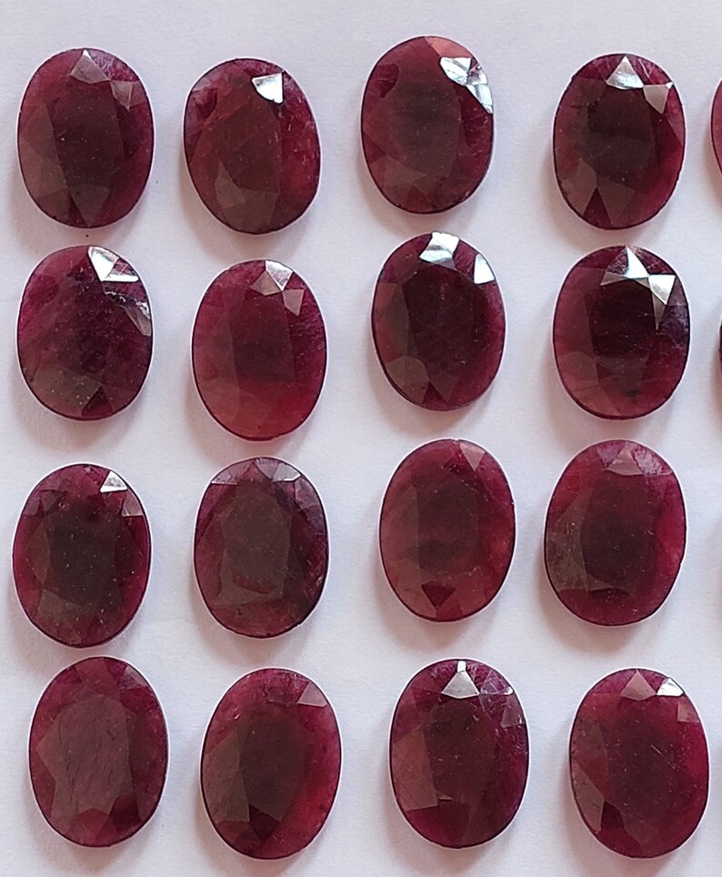 Puede incluir: Una colecci&oacute;n de 16 piedras preciosas ovaladas de color rojo oscuro. Las piedras preciosas son facetadas y tienen un acabado pulido.
