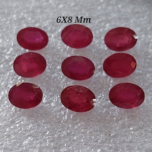 Può includere: Nove pietre preziose rosse di forma ovale, ciascuna misura 6x8 mm, sono esposte su una superficie bianca testurizzata.  6x8 Mm