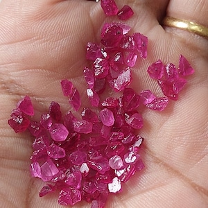 Könnte beinhalten: Eine Sammlung loser, facettierter Rubin-Edelsteine in verschiedenen Größen und Formen. Die Rubine sind tiefrot und haben einen hohen Glanz.
