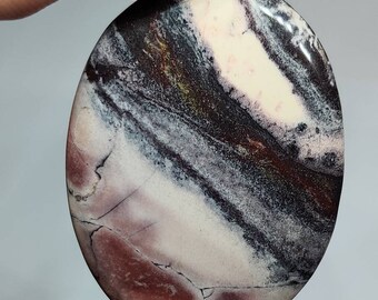 May include: A polished oval cabochon of banded agate with shades of white, gray, brown, and pink. The stone has a natural, organic pattern and is approximately 2 inches in diameter. The image includes the number 1384.