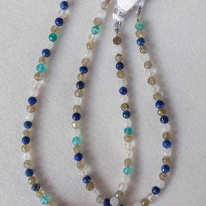 May include: Two strands of beaded necklaces with white, blue, and green gemstone beads. The necklaces have tassels on the ends.