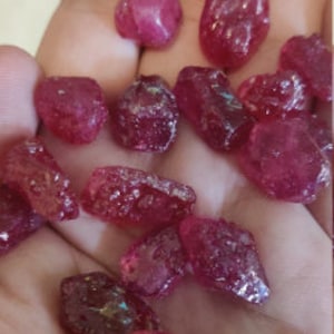 Puede incluir: Una colección de piedras preciosas de rubí facetadas sueltas, de varios tamaños y formas. Los rubíes son de color rojo intenso y tienen un acabado brillante.