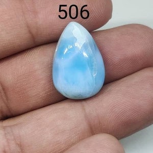Peut inclure: Une pierre précieuse cabochon bleu clair avec un motif marbré blanc et bleu. La pierre précieuse a la forme d'une larme et mesure environ 2,5 cm de long. La pierre précieuse est étiquetée avec le numéro 506.