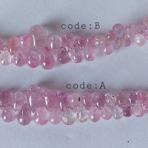 Könnte beinhalten: Zwei Reihen rosafarbener, tropfenförmiger Edelsteinperlen. Die obere Reihe ist mit "code: B" und die untere Reihe mit "code: A" beschriftet.