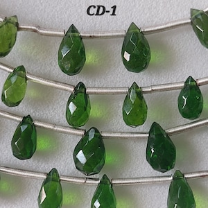 May include: Strands of faceted, teardrop-shaped green gemstones strung on silver-colored wire. The gemstones are a deep, emerald green color and have multiple facets that catch the light. The text "CD-1" is in the upper left corner.