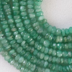 Puede incluir: Primer plano de hilos de cuentas de piedras preciosas verde esmeralda. Las cuentas tienen forma irregular con superficies facetadas, creando un efecto brillante. Las cuentas están ensartadas, lo que sugiere un collar o una pulsera.