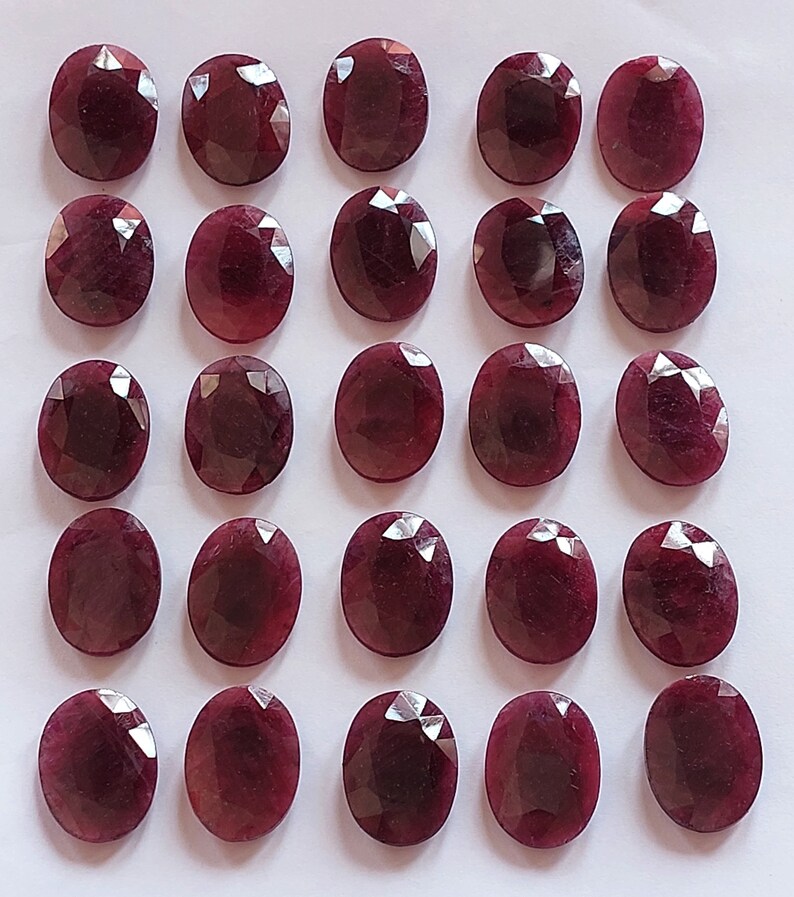 Puede incluir: Veinticinco piedras preciosas de rub&iacute; de forma ovalada y facetadas. Los rub&iacute;es son de color rojo intenso y tienen un acabado pulido.