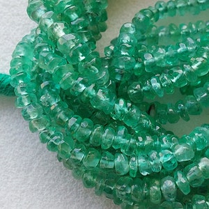 Puede incluir: Una hebra de cuentas de piedras preciosas de color verde esmeralda. Las cuentas son facetadas y tienen una forma ligeramente irregular. Las cuentas están enhebradas en un hilo transparente.