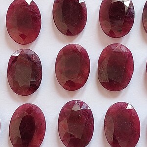 Puede incluir: Una colecci&oacute;n de 12 piedras preciosas ovaladas de color rojo oscuro. Las piedras preciosas son facetadas y tienen un acabado pulido.