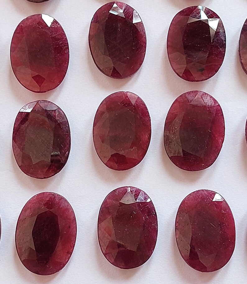 Puede incluir: Una colecci&oacute;n de 12 piedras preciosas ovaladas de color rojo oscuro. Las piedras preciosas son facetadas y tienen un acabado pulido.