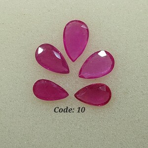 Peut inclure: Cinq pierres précieuses en forme de poire rose sur un fond blanc. Code : 10