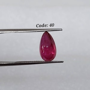 Può includere: Una pietra preziosa di forma a pera di colore rosso intenso tenuta da una pinzetta. La pietra preziosa è liscia e lucente. Codice: 40