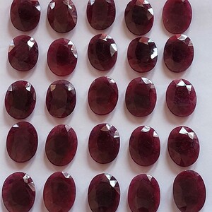 Puede incluir: Veinticuatro piedras preciosas ovaladas de color rojo oscuro dispuestas en cuatro filas de seis. Las piedras preciosas son lisas y pulidas.