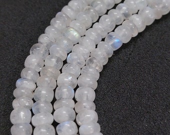 Peut inclure: Un brin de perles de pierre de lune blanche avec un éclat iridescent. Les perles sont rondes et lisses, et elles sont enfilées sur un fil transparent.