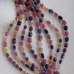 Puede incluir: Hebras de cuentas de piedras preciosas de colores en varios tonos de rosa, azul, amarillo y marrón. Las cuentas de forma ovalada están ensartadas, con borlas en los extremos. Es probable que las piedras preciosas se utilicen para la fabricación de joyas.