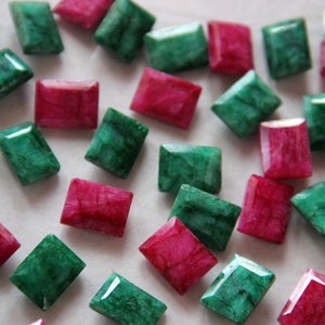 May include: A collection of emerald green and ruby red rectangular gemstones. The gemstones are faceted and have a polished finish.