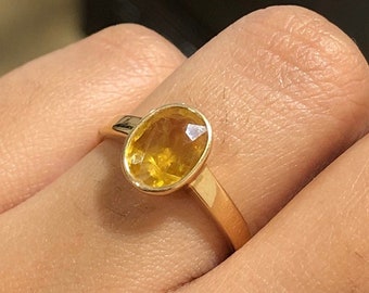 Puede incluir: Un anillo de oro con una piedra ovalada amarilla.