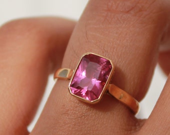 May include: A gold ring with a pink rectangular gemstone.